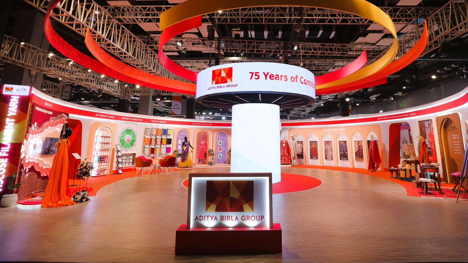 A striking showcase of various clothing pieces arranged for visual impact with a lighted sign in front that says 'Aditya Birla Group'.