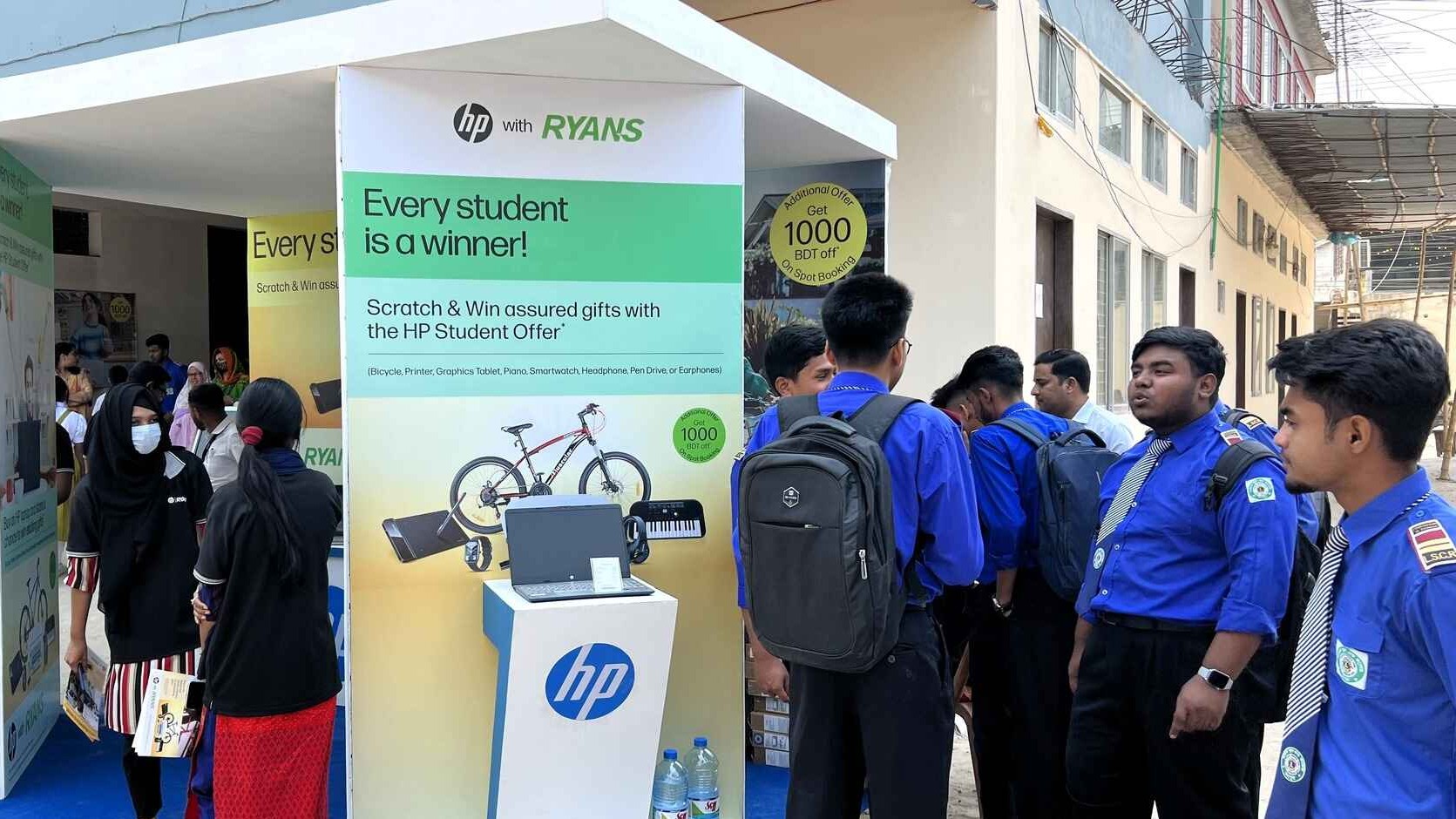 Students in blue uniforms gathering at the HP x Ryans Computers event booth, featuring HP laptops.