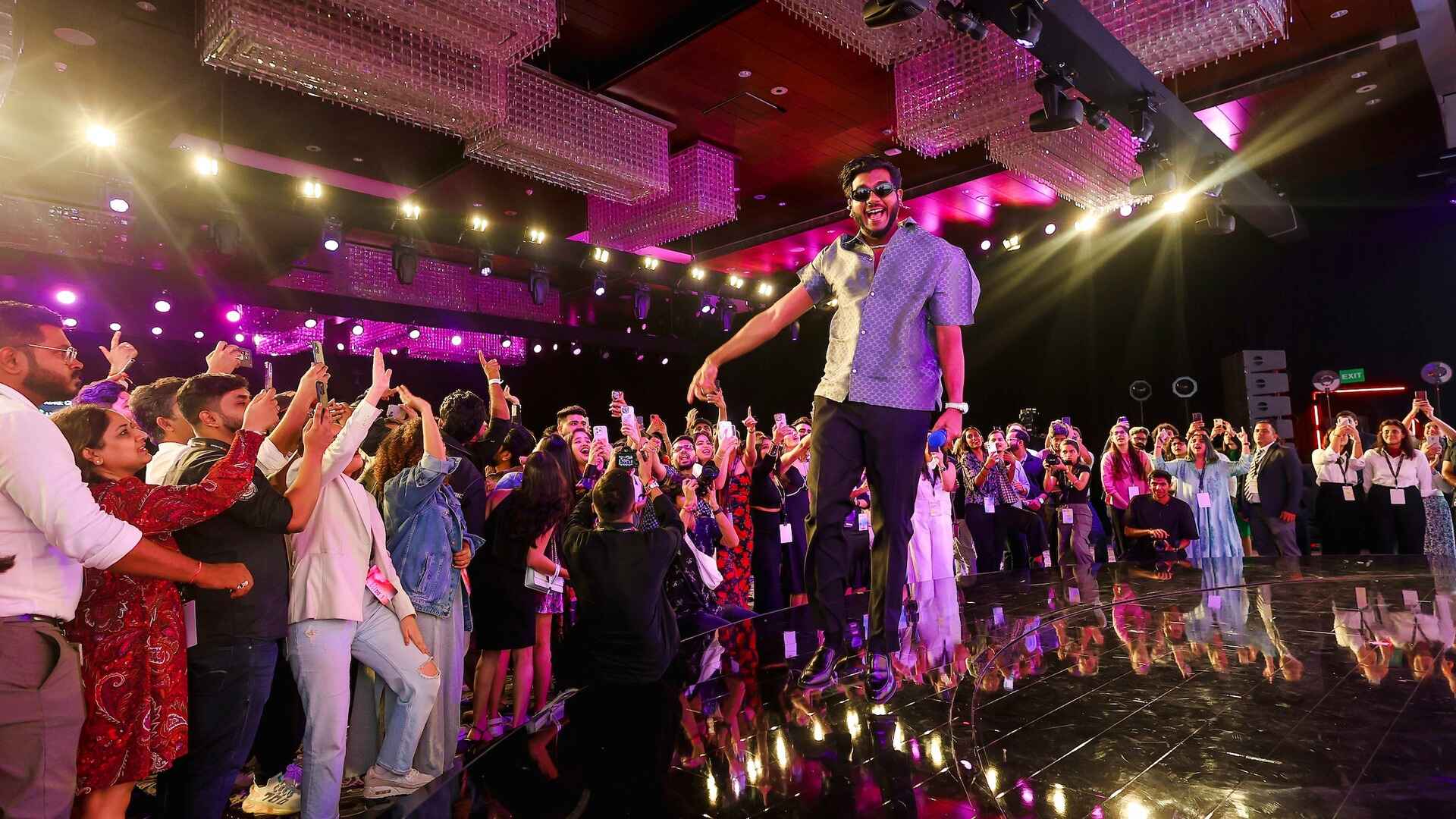 A singer jumps on stage, surrounded by an enthusiastic crowd of YouTube Brandcast 2024 India attendees.